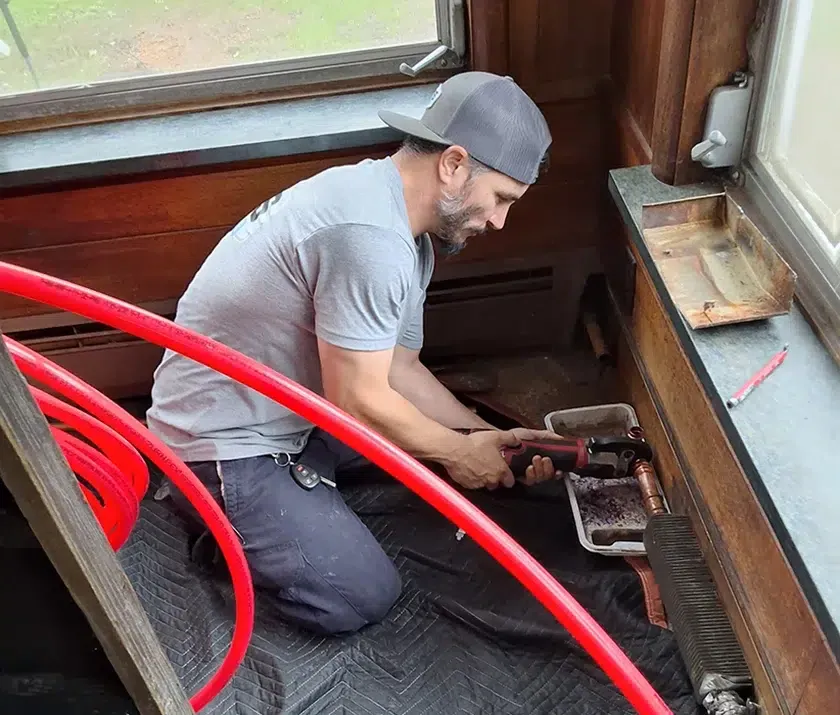 Technician running new HVAC lines during Cherry Hill system installation for Davis Heating and Air