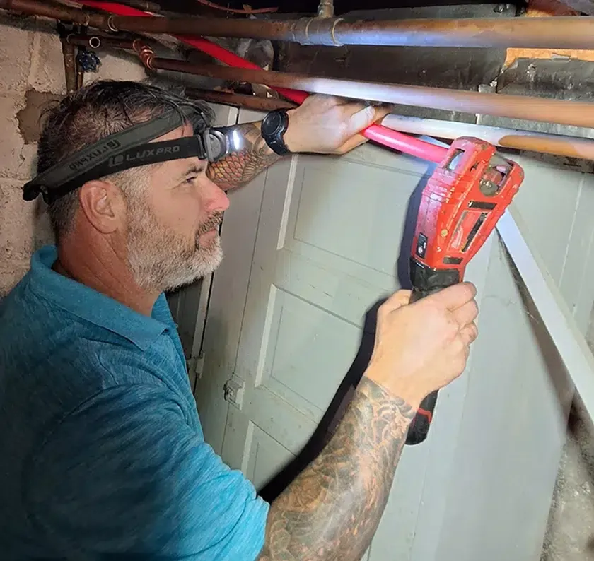 Davis Heating and Air technician using power tools for a basement HVAC repair in Cherry Hill