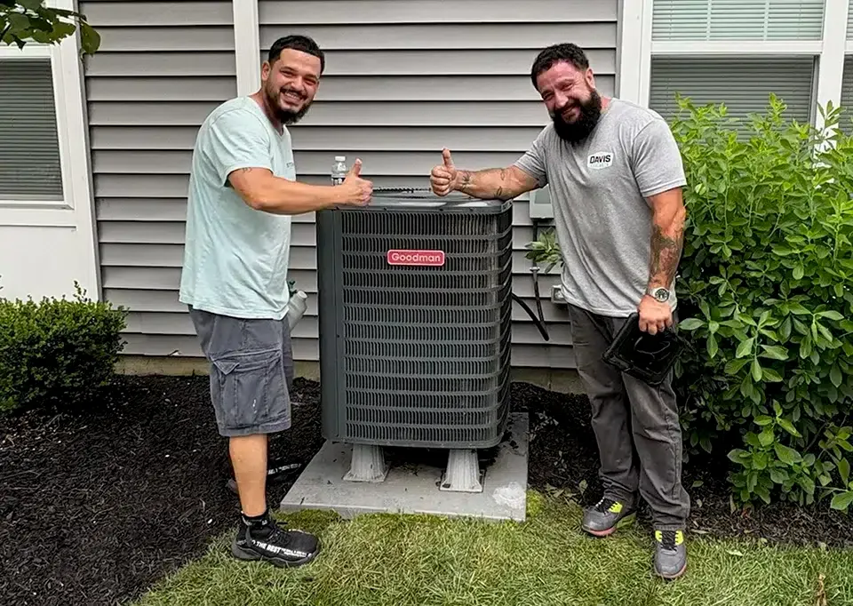 Two Davis Heating and Air technicians installing an outdoor HVAC unit in Cherry Hill