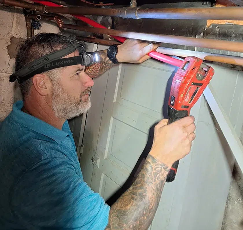 Davis Heating and Air technician using power tools for a basement HVAC repair in Cherry Hill